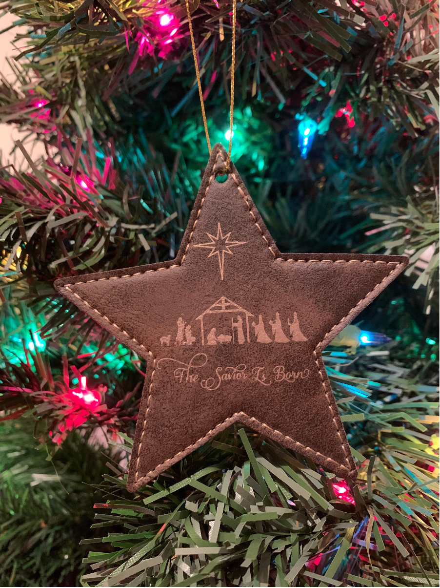 Star-shaped Christmas ornament with engraved design on a decorated tree